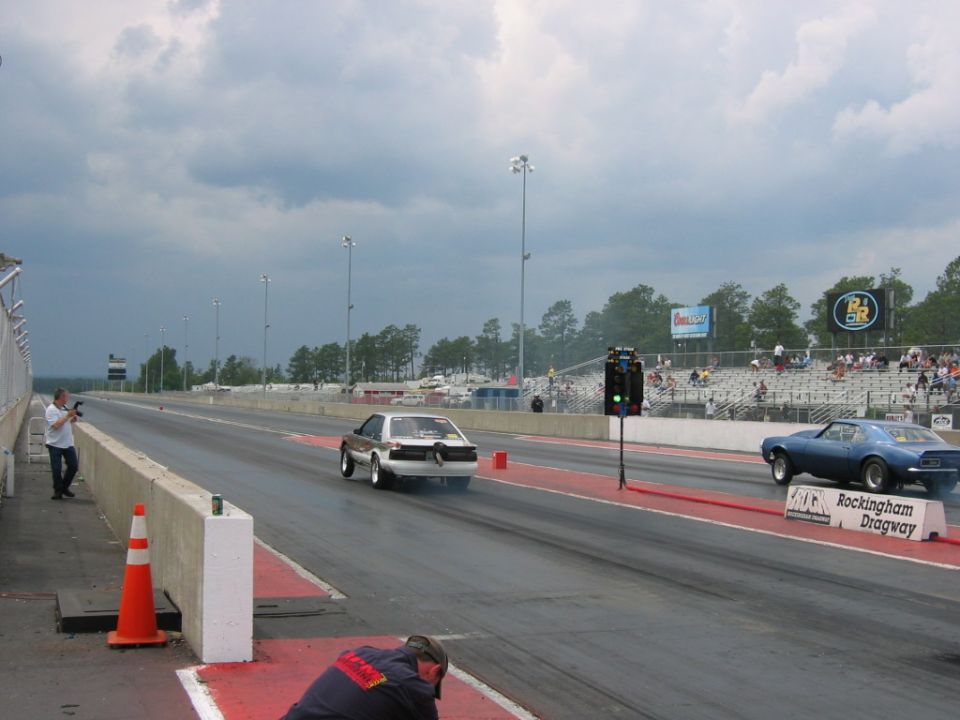 1992 Ford Mustang racing down drag strip, rear view, white with brown stripes
