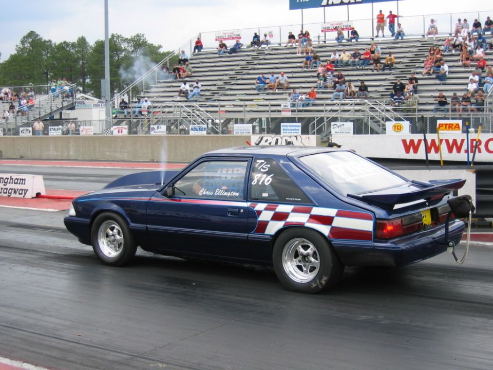 Blue Ford Mustang drag car with checkerboard stripe and Chris Ellington 816 on door, at Rockingham Dragway