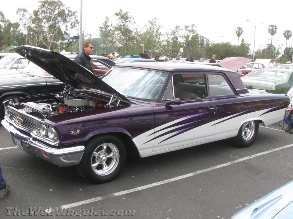 Purple and white 1963 Ford Galaxie two-door sedan with custom side graphics and hood open, parked in a lot