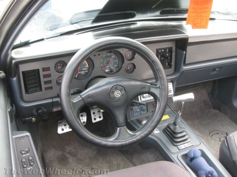 1968 Ford Mustang - The interior of a car shows the dashboard, steering wheel, and center console with a shifter and a small stuffed toy.