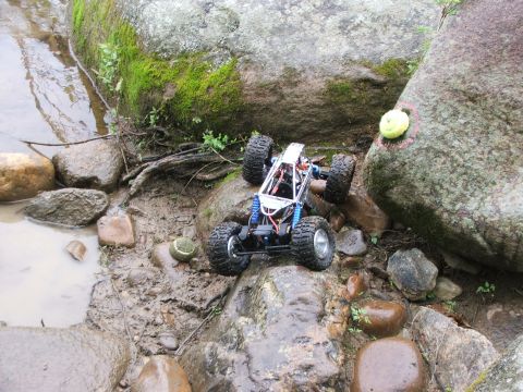 1996 Ford Bronco - A remote control rock crawler navigates a challenging terrain of mud and rocks next to a stream.
