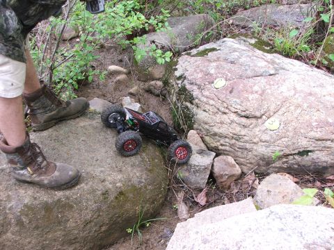 1996 Ford Bronco - A remote control rock crawler navigates a challenging outdoor course with large rocks and mud.