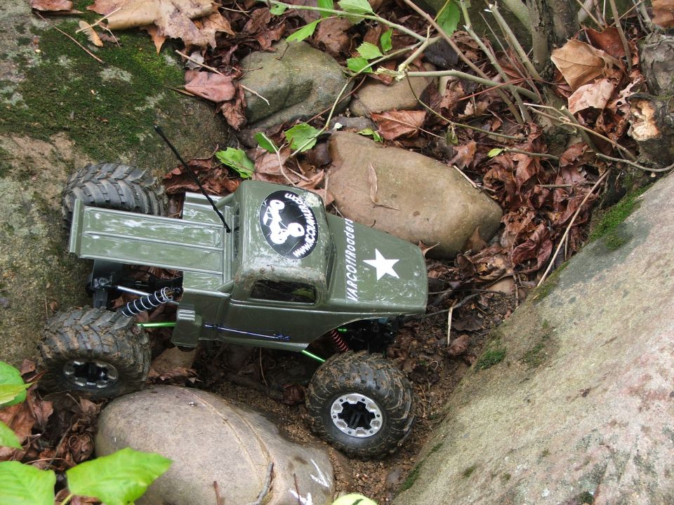 Green RC rock crawler truck with VARCOffroaders text and a star on the hood, on rocks and dirt