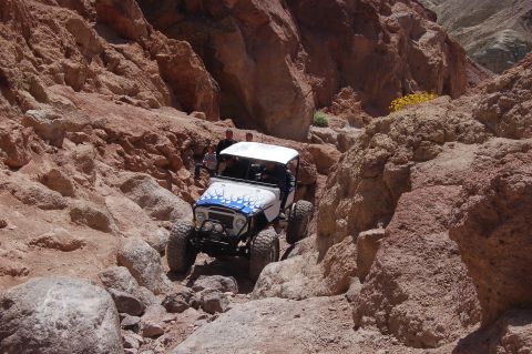 1985 Ford Bronco - A modified off-road vehicle navigates a narrow, rocky canyon path.