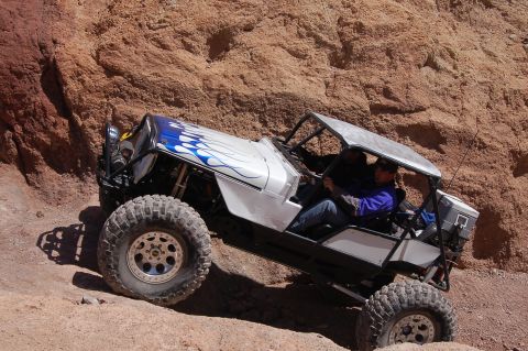 1985 Ford Bronco - A modified off-road vehicle navigates a steep, rocky incline in a desert landscape.