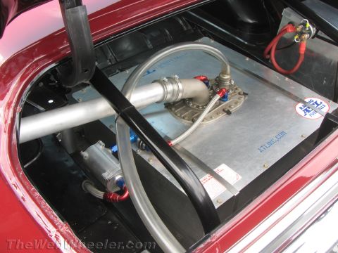 1968 Ford Mustang - The trunk of a vehicle shows an ATL fuel cell with associated plumbing and a battery connection.