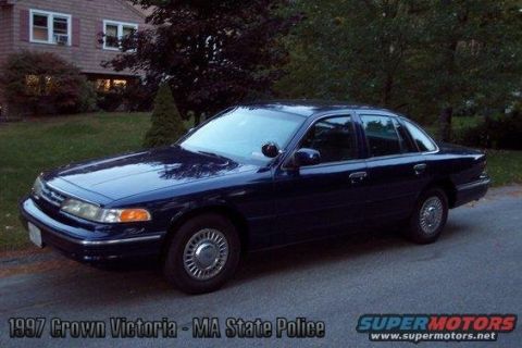 2001 Ford Crown Victoria - This dark blue 1997 Ford Crown Victoria sedan is seen from a three-quarter front view, parked on a street with a house in the background.