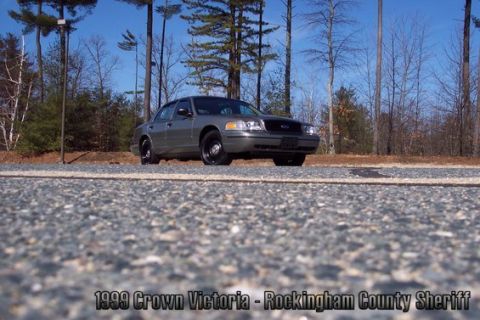2001 Ford Crown Victoria - A gray 1999 Ford Crown Victoria is parked outdoors with a wooded background.