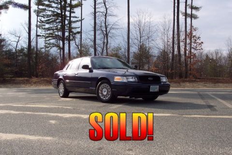 2001 Ford Crown Victoria - This dark blue 2001 Ford Crown Victoria is shown from a 3/4 front view, parked outdoors with a wooded area behind it.