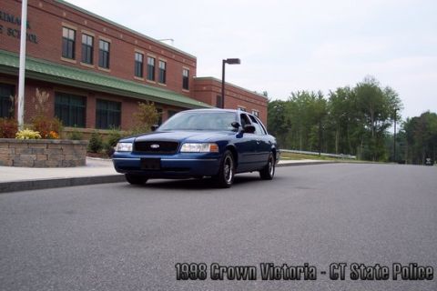 2001 Ford Crown Victoria - A blue 1998 Ford Crown Victoria, marked as CT State Police, is parked on asphalt in front of a school building.