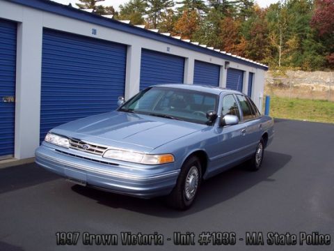 2001 Ford Crown Victoria - A blue sedan, identified as a 1997 Crown Victoria, is parked outside storage units.