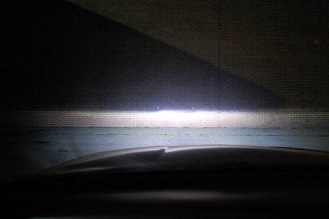 1985 Mercury Grand Marquis - View from inside a car at night, with headlights casting a bright beam onto a brick wall.