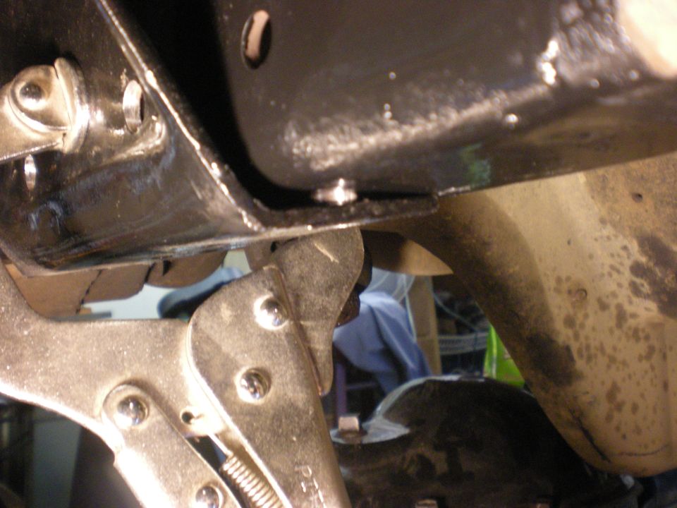 Close-up of black metal frame with vise grips attached to suspension component