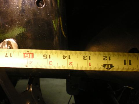 1993 Ford Bronco - A yellow tape measure is used to measure a section of a dark-colored vehicle frame.