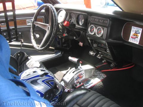 1968 Ford Mustang - The interior of a modified car features racing seats, a helmet, a prominent shifter, and additional gauges.
