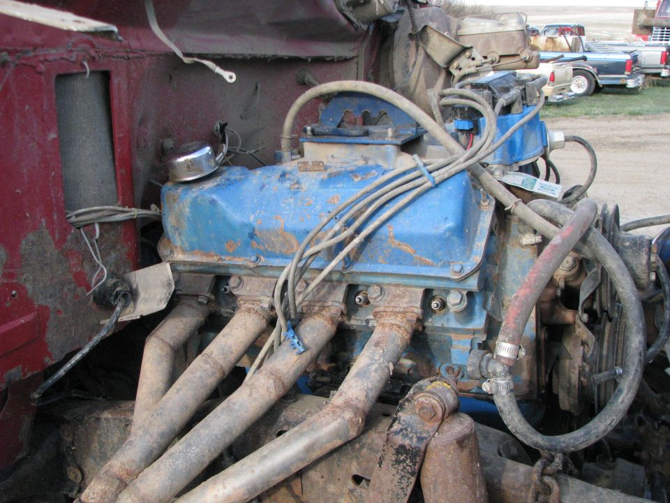 Blue engine with rusty exhaust manifolds, viewed from the front