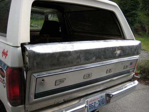 1980 Ford Bronco - The rear tailgate of a classic Ford Bronco shows the iconic 'FORD' lettering and an American flag decal.