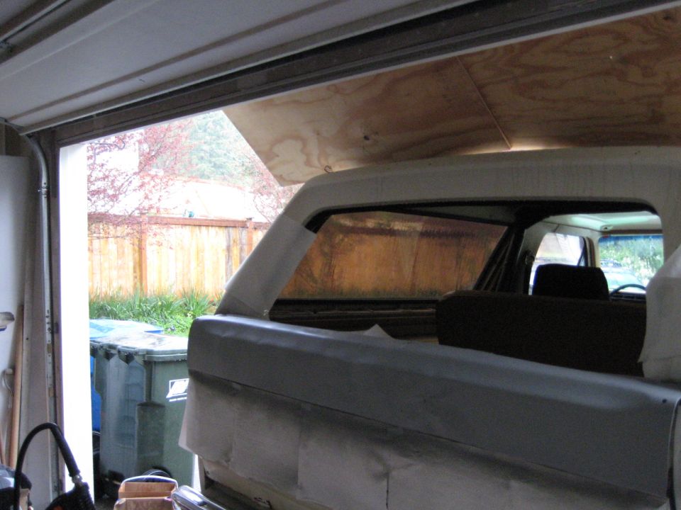 White 1980 Ford Bronco in a garage, rear view, undergoing restoration