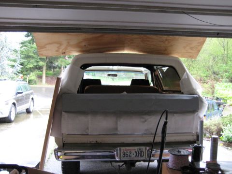 1980 Ford Bronco - 1980 Ford Bronco rear view, undergoing bodywork in a garage. Another vehicle is parked outside.