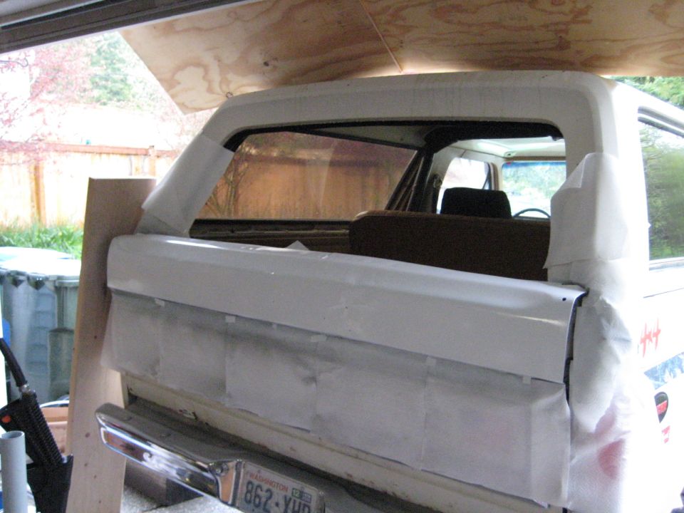 Rear of a white Ford Bronco, taped up for paint. Washington license plate visible