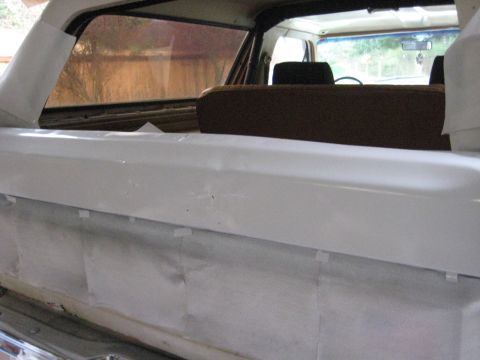 1980 Ford Bronco - The interior of a vehicle shows a white painted panel and brown seats, with masking tape applied.