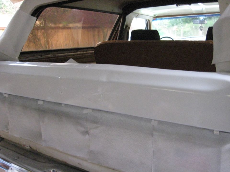 White painted interior panel with masking tape, brown seats, and tinted rear window