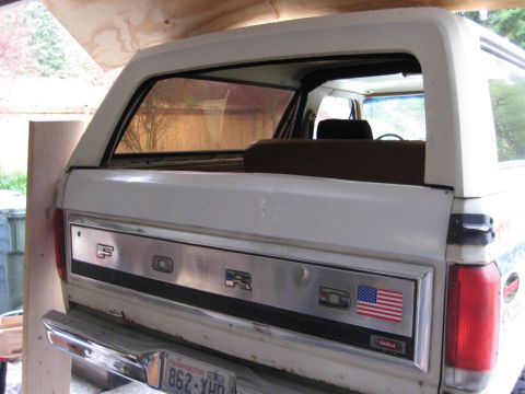 1980 Ford Bronco - The rear of a white 1980 Ford Bronco shows the tailgate with 'FORD' lettering and an American flag decal.