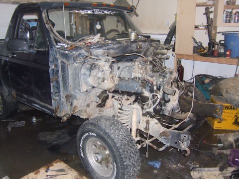 1989 Ford Bronco - This Ford truck chassis is in a state of disassembly, showing the engine bay and front suspension components.