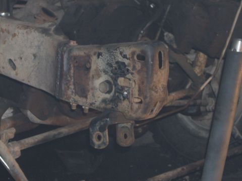 1989 Ford Bronco - Detail of a heavily rusted bracket on a vehicle's chassis.
