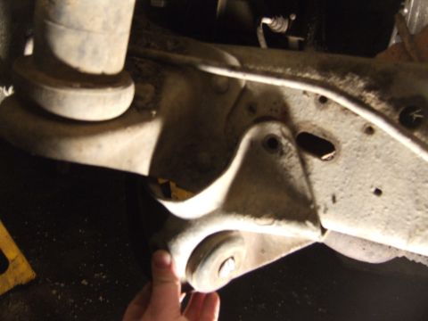 1989 Ford Bronco - A close-up view of a vehicle's suspension system, with a hand visible near a component.