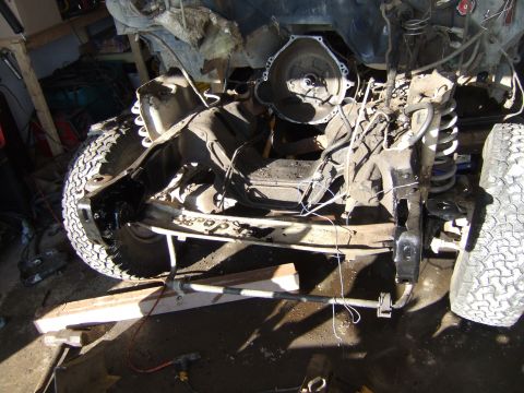 1989 Ford Bronco - The vehicle's frame and drivetrain components are exposed, with the transmission removed for work.