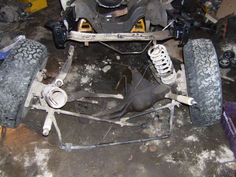 1989 Ford Bronco - Disassembled vehicle frame and suspension components are visible, resting on a workshop floor.