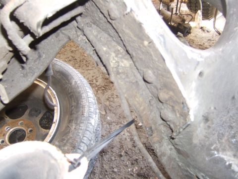 1989 Ford Bronco - Detail shot of the undercarriage, showing rust and a tire within the wheel well.