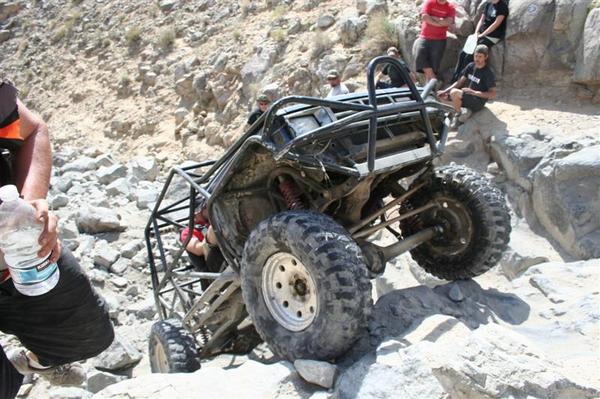 Off-road buggy with roll cage navigating rocky terrain