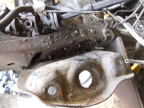 1989 Ford Bronco - Underside view of heavily corroded vehicle frame and engine components, showing signs of wear and tear.
