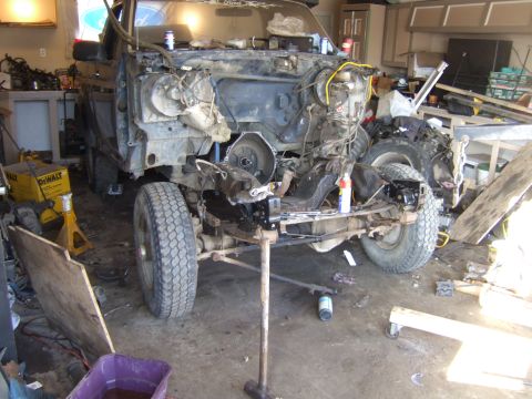 1989 Ford Bronco - This vehicle is undergoing extensive mechanical work, with the engine removed and the front end partially dismantled.