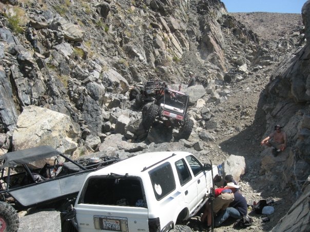 1993 Toyota 4Runner and two off-road buggies on a rocky mountain trail. People are working on the 4Runner