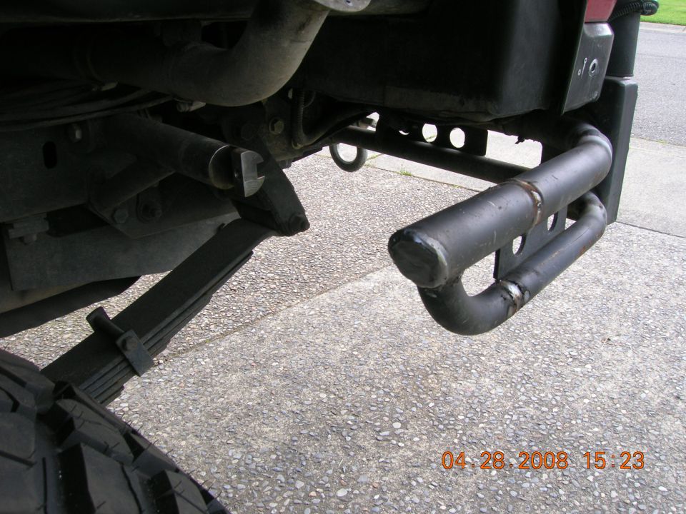Fabricated black tube rear bumper and leaf spring under a truck's rear corner