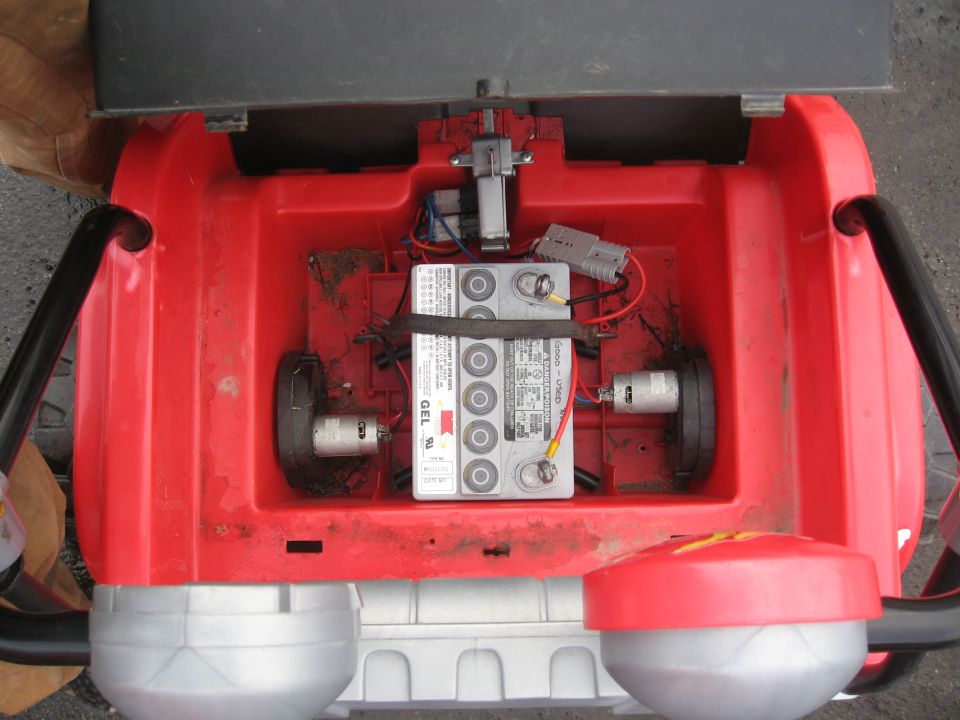 Open red housing showing a GEL battery, two electric motors, and wiring. Supermotors.net logo visible