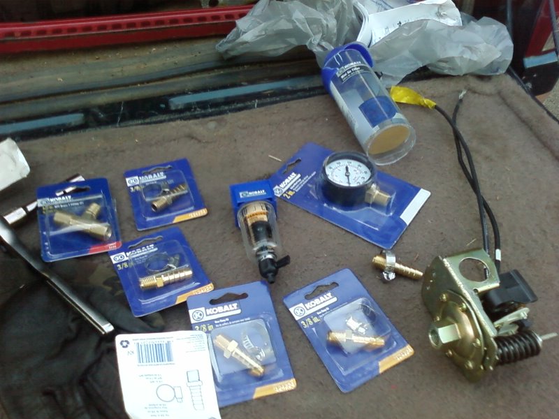 Air compressor parts and gauge laid out on a brown surface