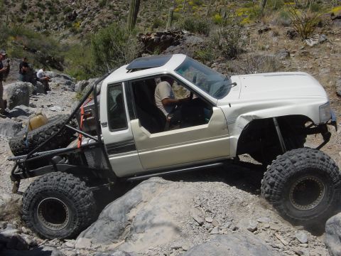 1986 Toyota Hilux - This modified pickup truck, likely from the late 1980s, is shown tackling a challenging rocky trail.
