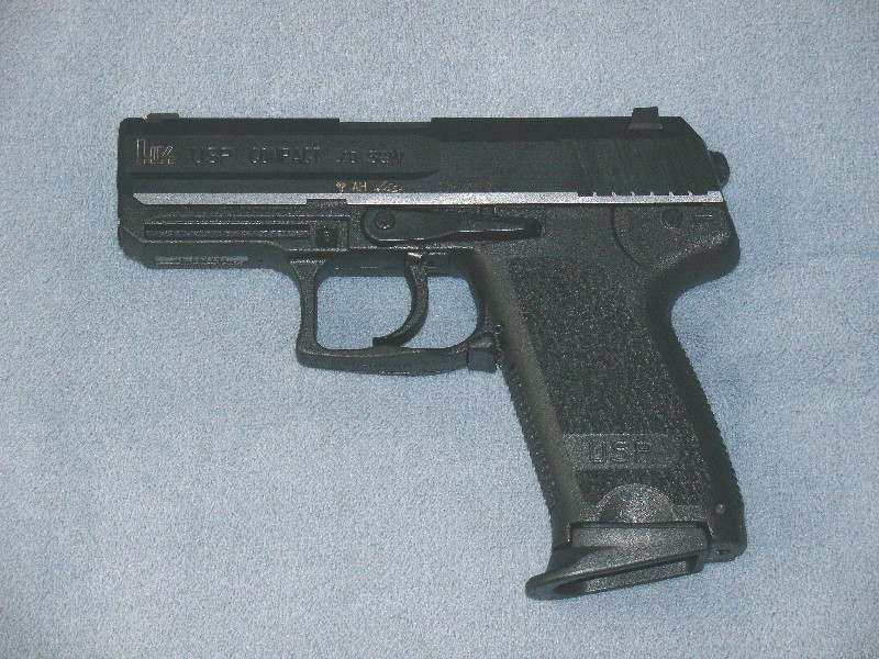 Black HK USP semi-automatic pistol photographed left-side on gray fabric