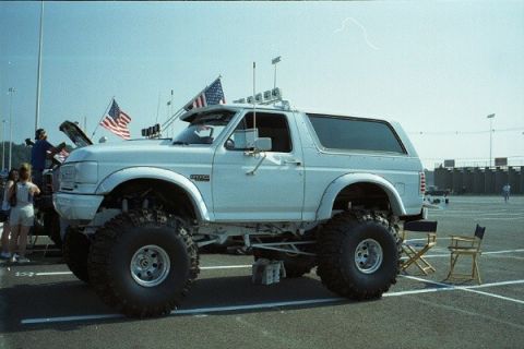 1981 Ford Bronco - A lifted white Ford Bronco is parked outdoors with American flags displayed.