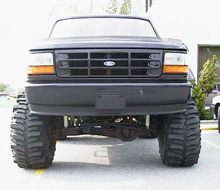 1981 Ford Bronco - This lifted Ford truck features a prominent black grille and oversized tires, suggesting a model year around 1992.