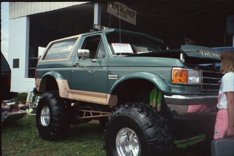 1981 Ford Bronco - This lifted Ford Bronco features a two-tone paint scheme and aggressive off-road tires, with its hood open.