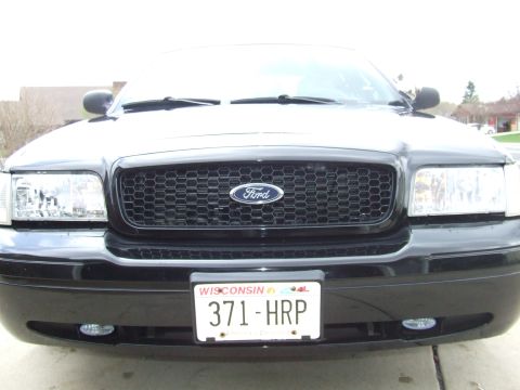 2003 Ford Crown Victoria - Front view of a black Ford Crown Victoria with a honeycomb grille and a Wisconsin license plate reading "371-HRP".