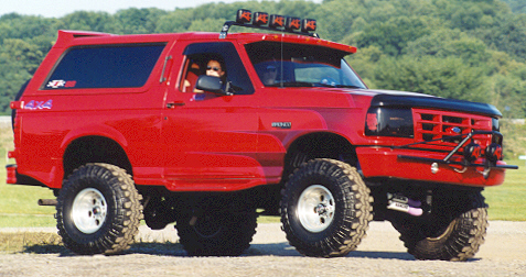 1981 Ford Bronco - This red Ford Bronco, likely a 1992 model, is equipped for off-road use with large tires and a winch.