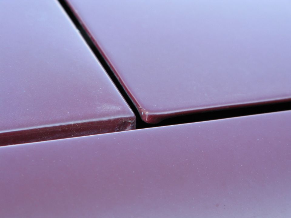 Close-up of the seam between two dark red vehicle body panels.