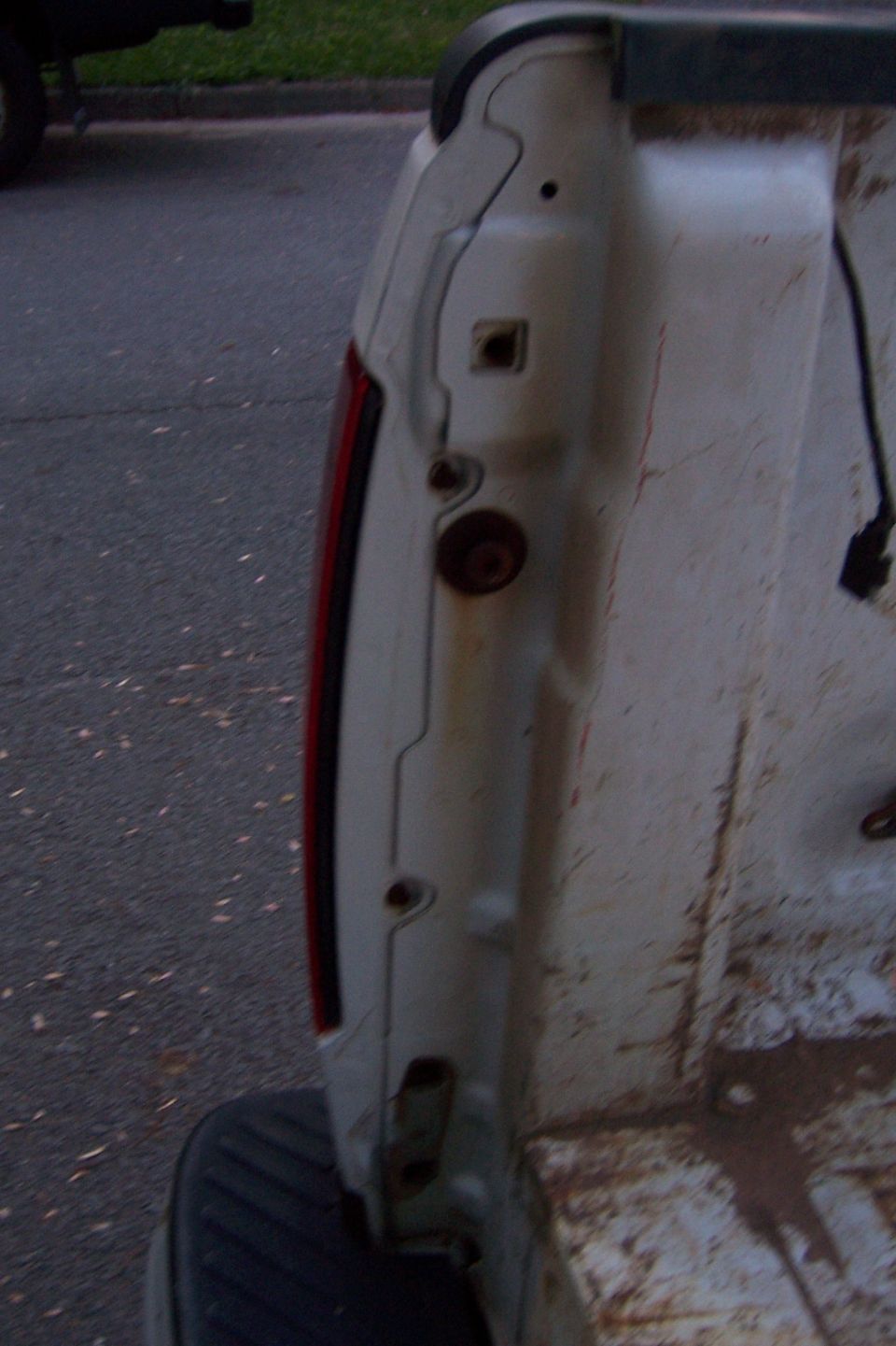 Close-up of a white pickup truck bed, showing taillight and weathered interior.
