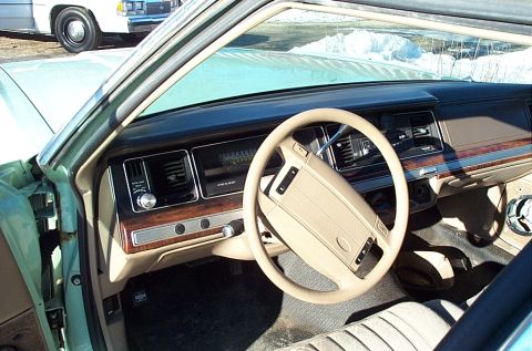 2001 Ford Crown Victoria - The interior of a 2001 Ford Crown Victoria, with a light tan steering wheel and wood-grain trim on the dashboard.
